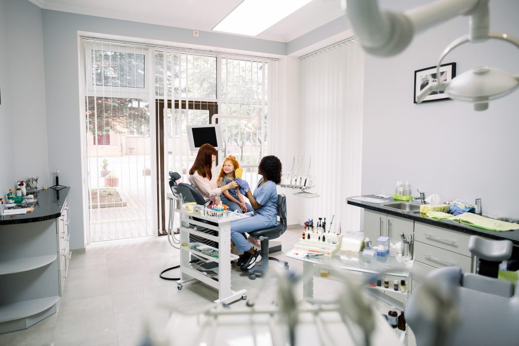 Pediatric dental office with dentist and hygienist examining young patient